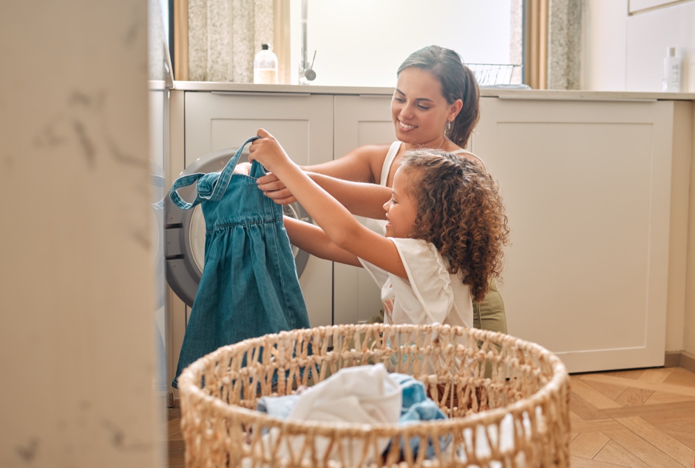 Parent and child doing laundry together at home