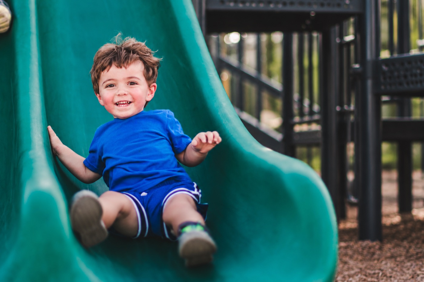 Smiling child playing on a playground slide
